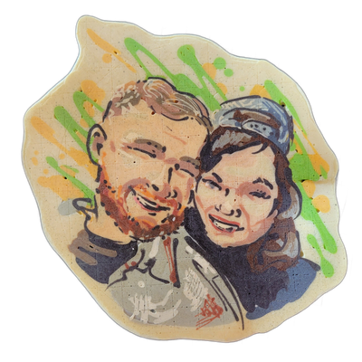 Pancake art portrait of two adults shown from the shoulders up, cheek to cheek and smiling; the figure on the left has short light-brown hair, a beard, and wears a gray jacket, while the figure on the right has dark brown hair pulled back under a light blue cap and wears a blue top. The portrait is…