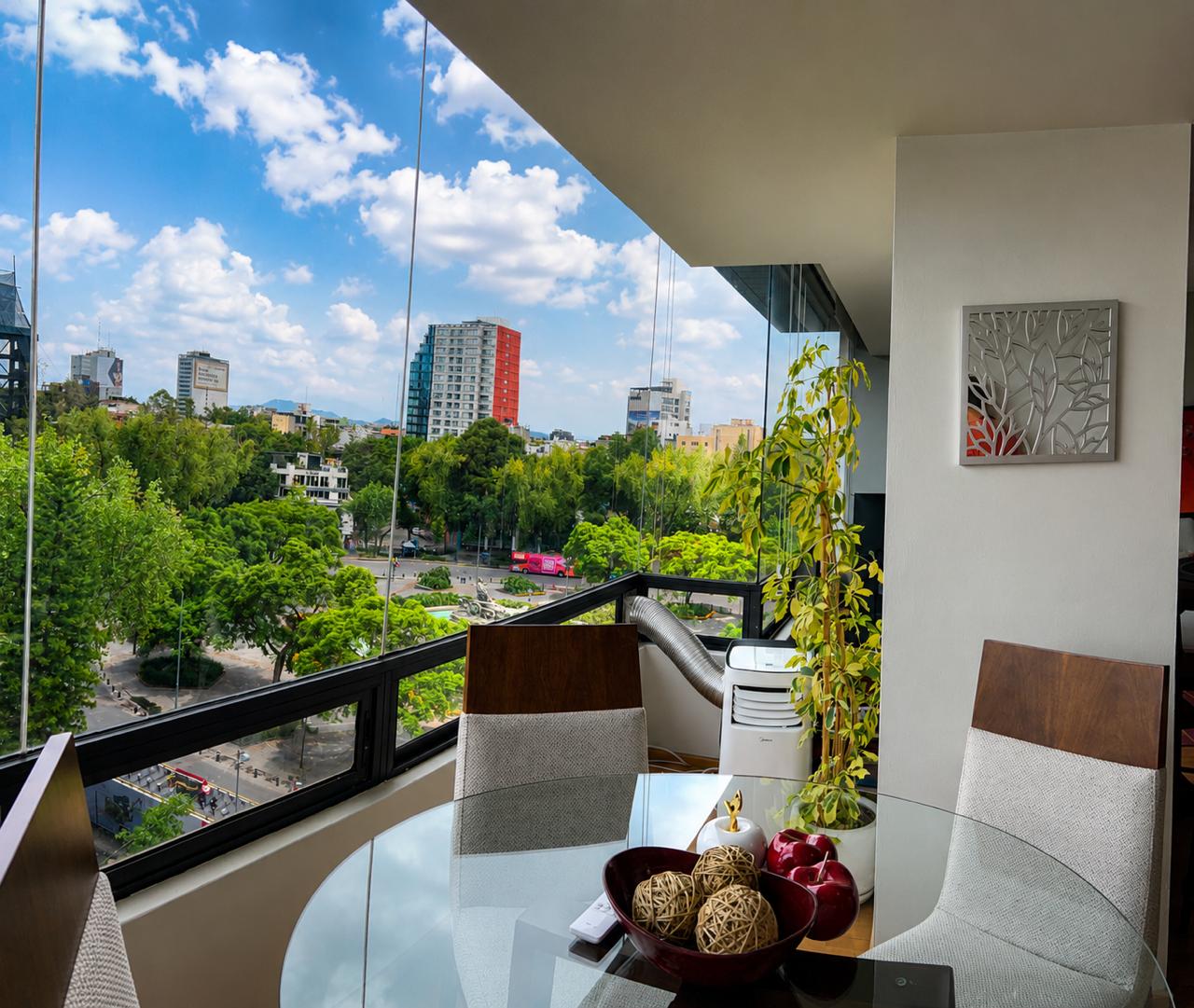 Balcony dining table overlooking a tree-lined street and city buildings.