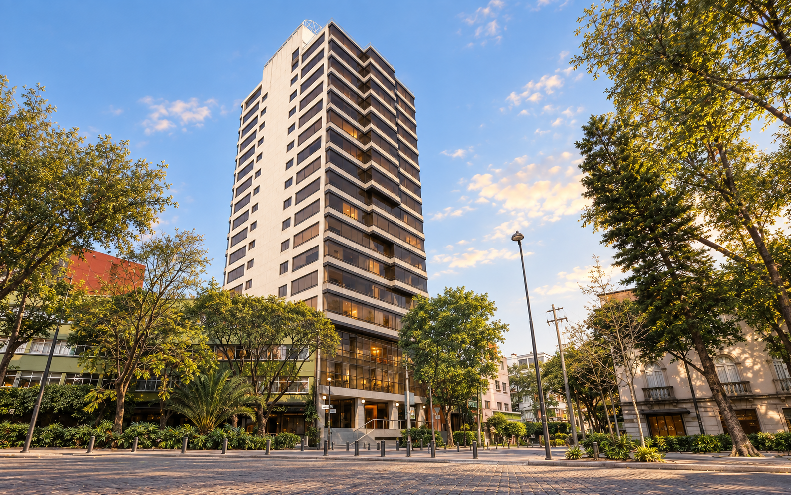 Tall apartment building framed by trees along a city street.