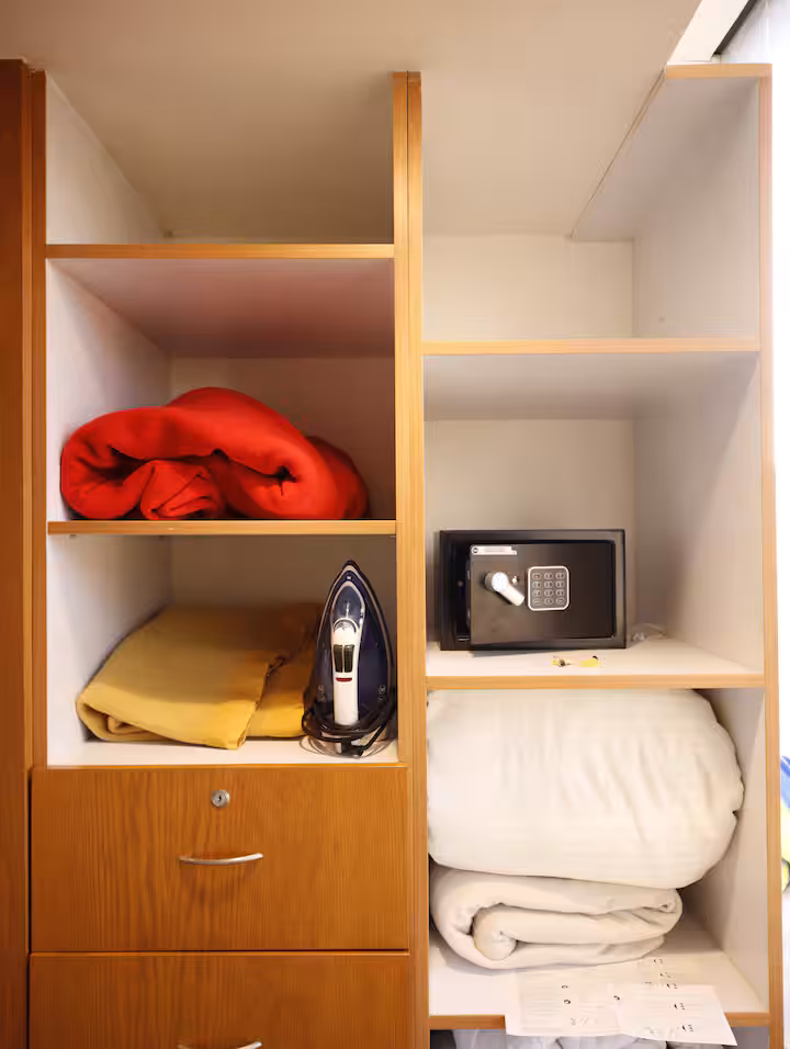 Closet shelves with folded linens and an iron.