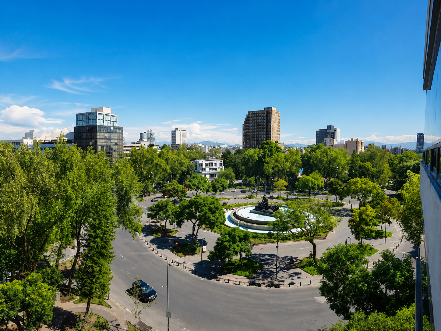 Tree-lined roundabout and city buildings seen from a window.