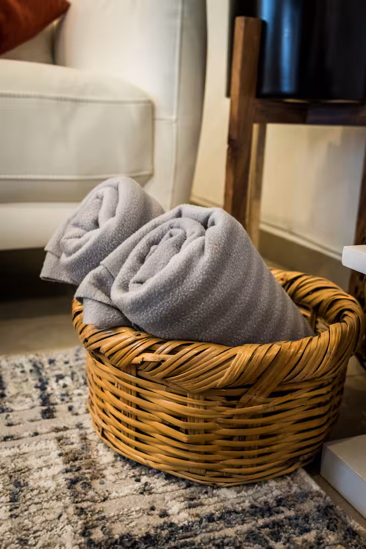 Basket with rolled towels beside a sofa.