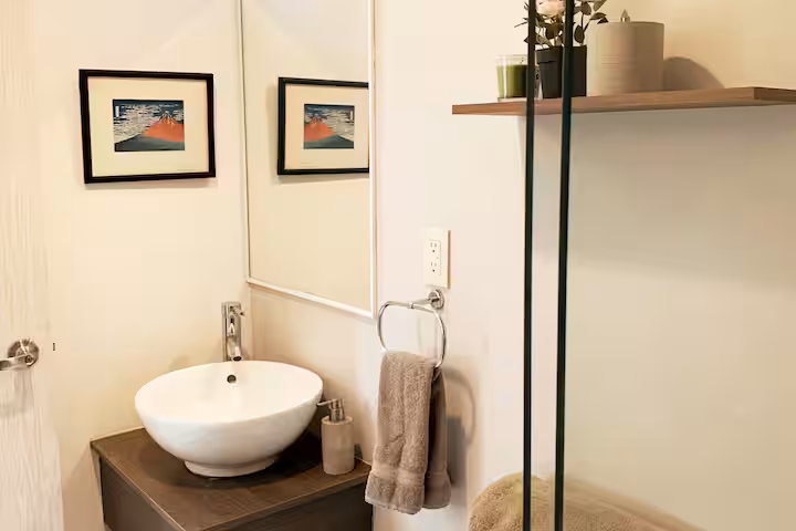 Bathroom vanity with a vessel sink, mirror, and framed wall art.