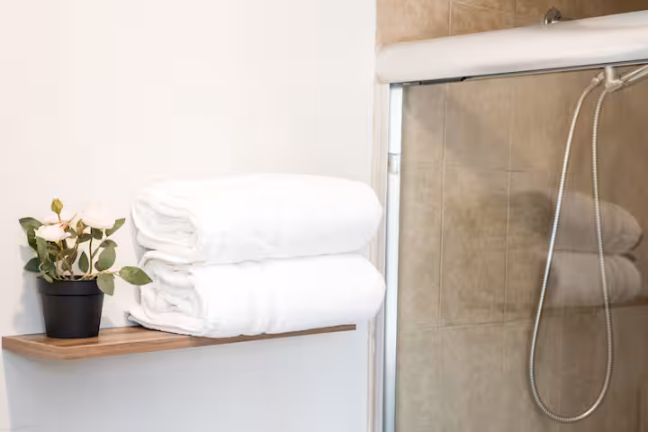 Folded white towels beside a tiled shower.