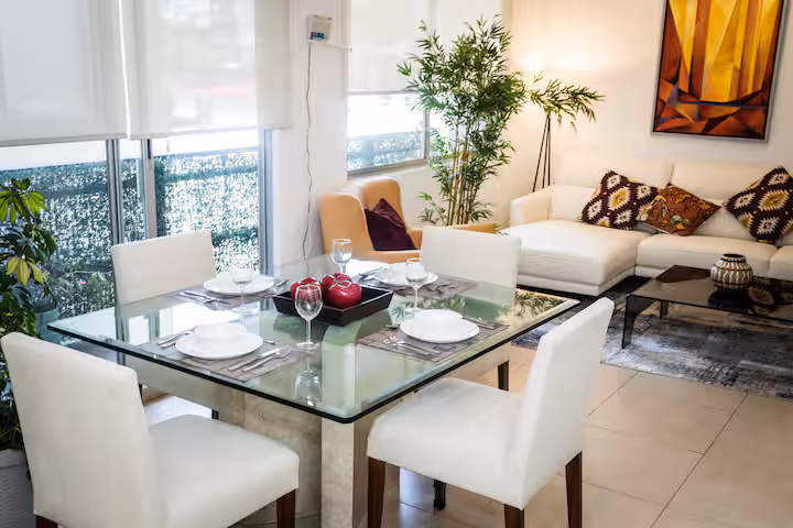 Glass dining table with four chairs beside the living room.