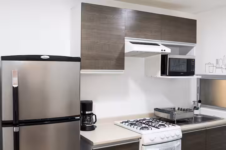 Kitchen with a refrigerator, gas stove, microwave, and coffee maker.