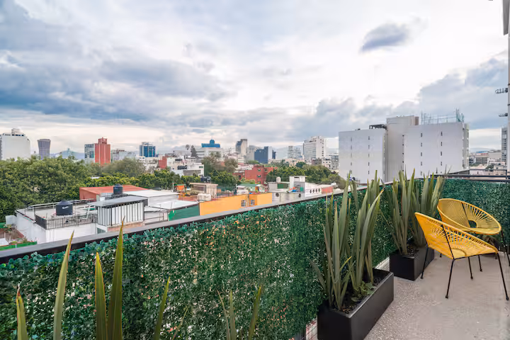 Balcony with two yellow chairs, planters, and a city skyline.