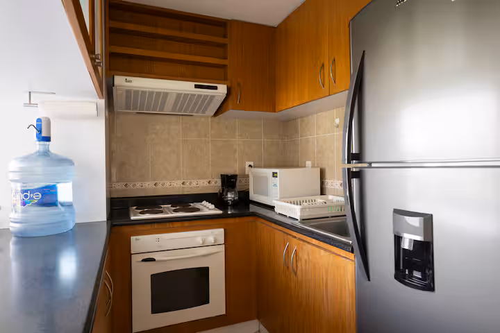 Kitchen with wood cabinets, refrigerator, stove, microwave, and coffee maker.