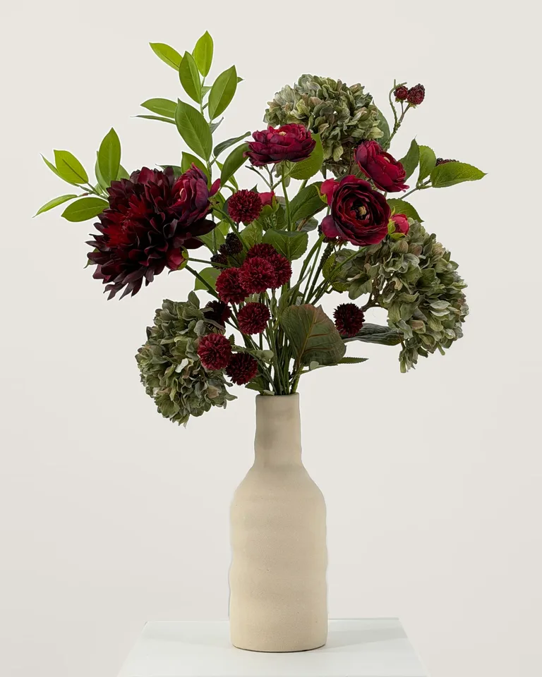 Zijden boeket Rubina met burgundy bloemen en groene hortensia in een beige vaas op een witte sokkel
