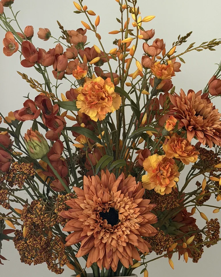 Detail van oranje dahlia’s, kleine bloemen en fijne takken.