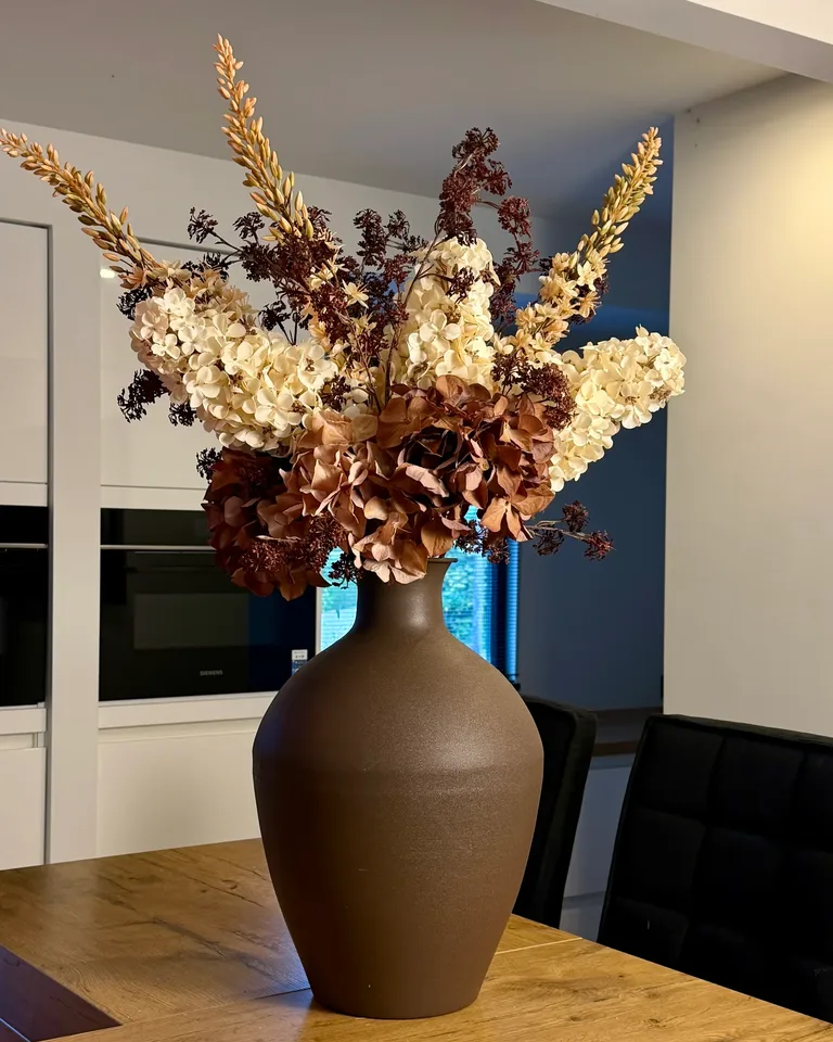Cassia met crème en bruine hortensia’s op een kookeiland in een lichte keuken