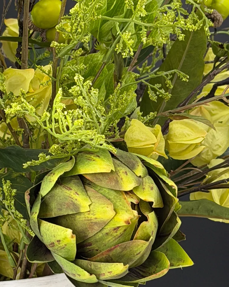 Detail van een groene artisjok tussen physalis en fijne takken in boeket Verdea.