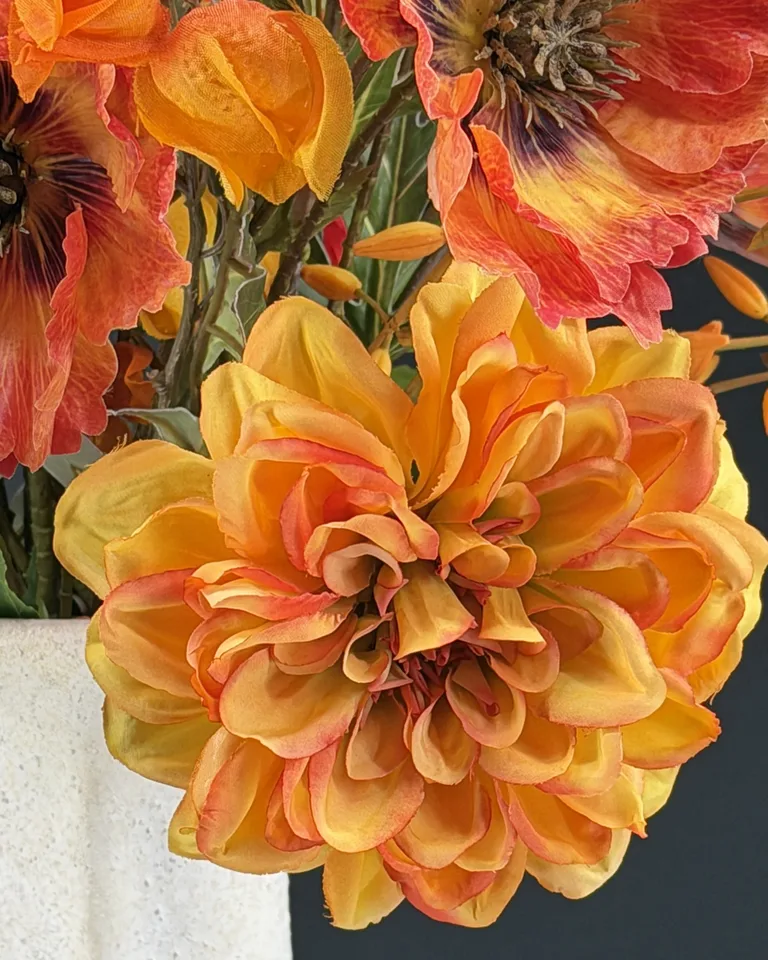 Detail van oranje bloemen en groene takken in Calista