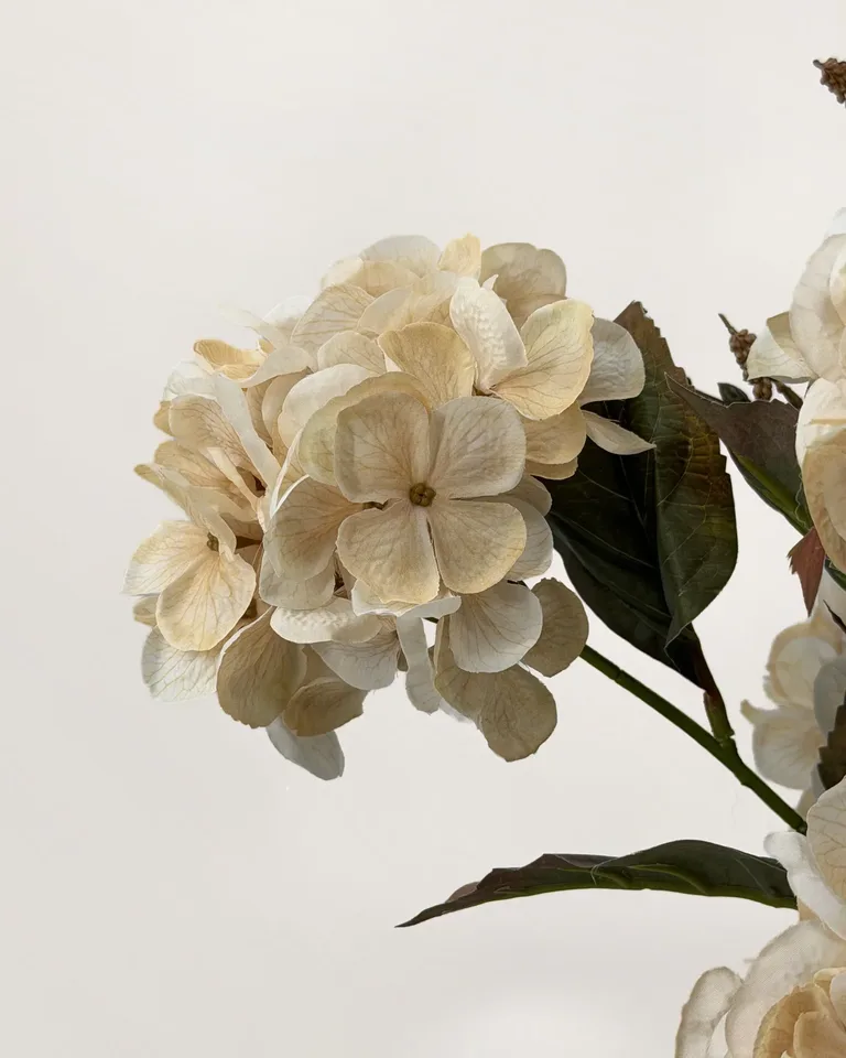 Odette. Weelderig rond boeket met crèmekleurige hortensia’s.