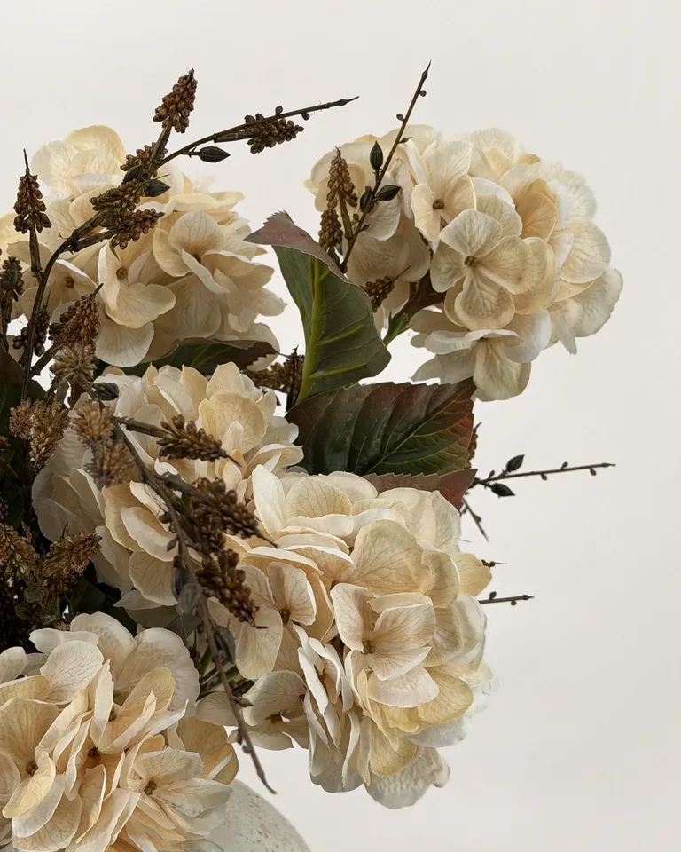 Odette. Weelderig rond boeket met crèmekleurige hortensia’s.