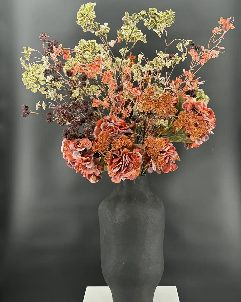 Opgaand boeket Sienna met bruine, oranje en groene bloemen en takken.