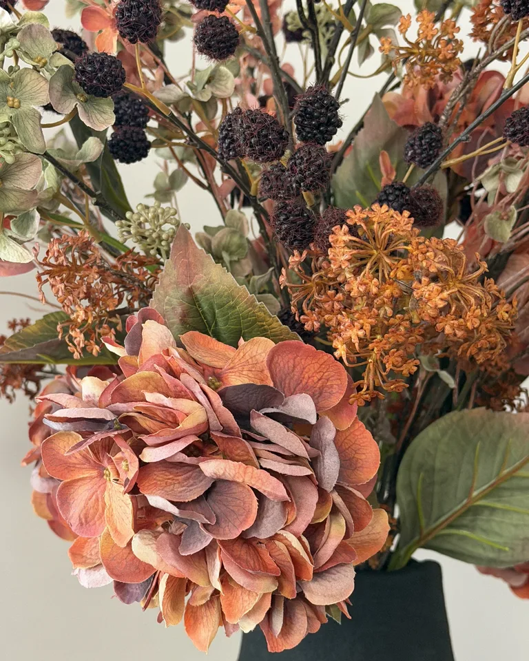 Detail van Sienna met donkere bessen en een oranje hortensia.