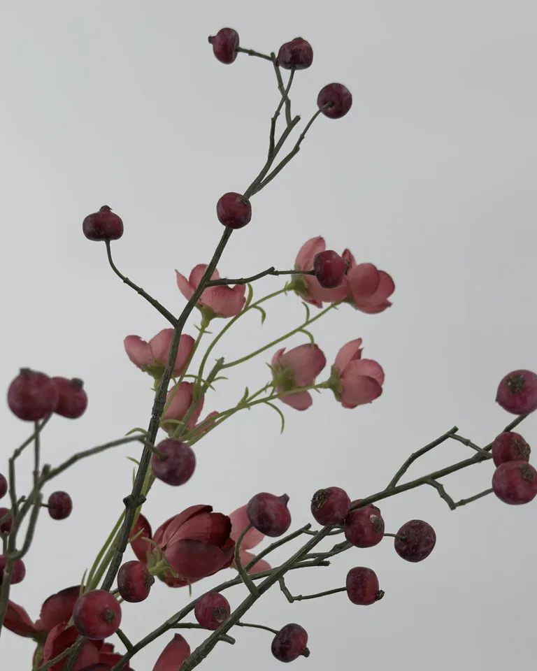 Detail van bessentakken en fijne takken tussen mauve bloemen in boeket Liora.