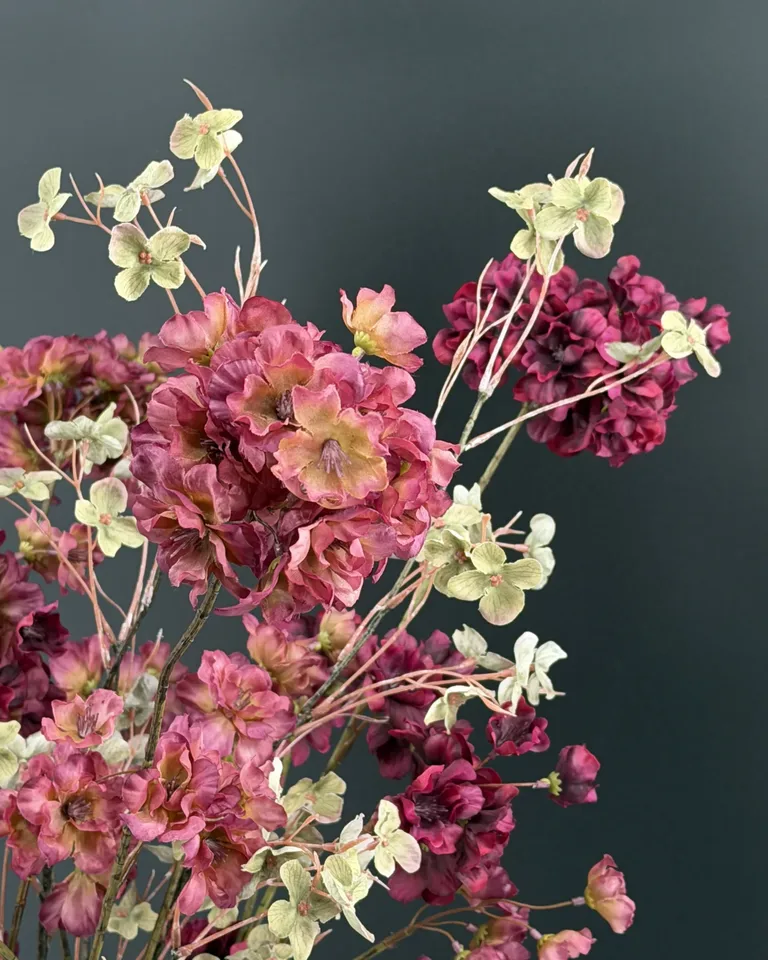 Detail van roze en bordeaux bloesem met groene takken in Zarelle boeket
