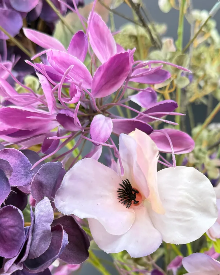 Detail van roze en paarse bloemstelen met een groene hortensiatak.