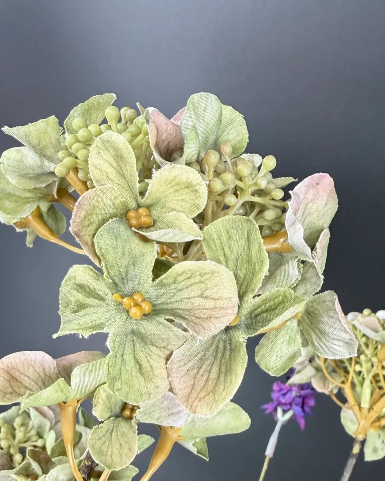 Detail van lavendelkleurige bloemen, paarse hortensia en groene takken.