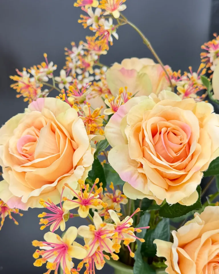 Detail van twee zalmroze rozen en gele takken uit Rosa boeket.