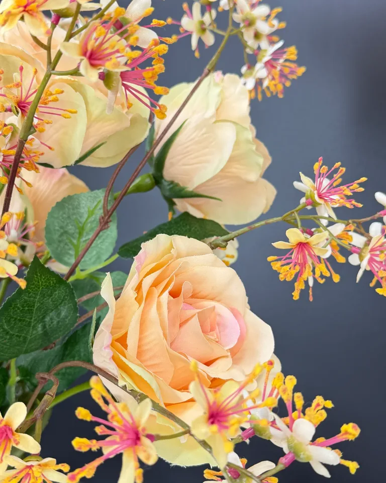 Detail van een zalmroze roos met fijne bloemen en groen uit Rosa boeket.