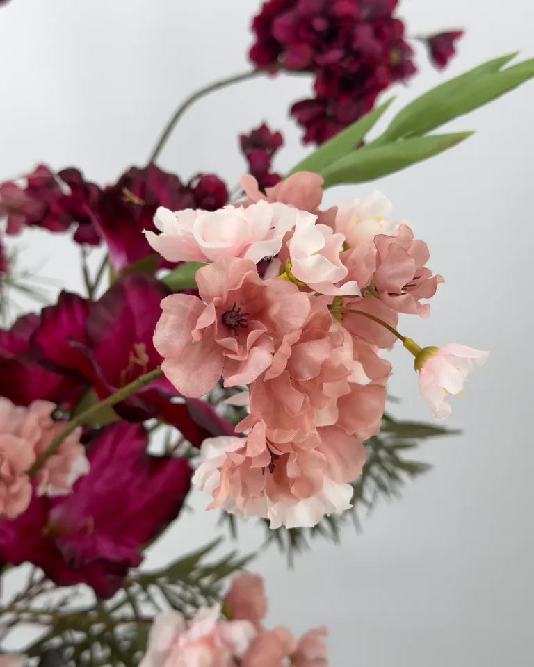 Amora. Fleurig asymmetrisch boeket in burgundy en roze tinten.
