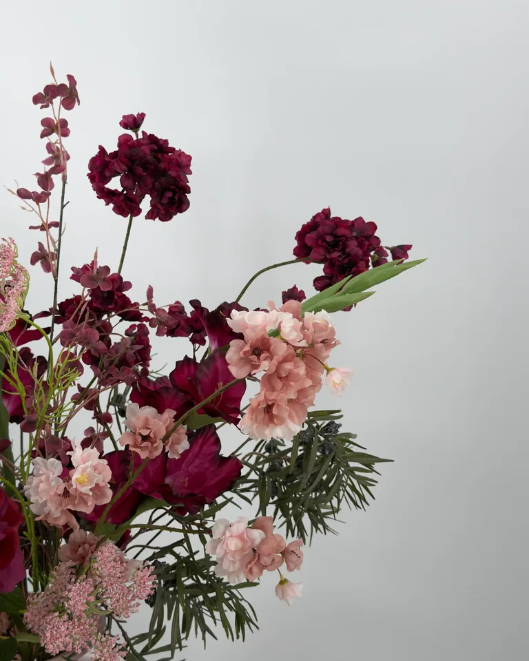 Amora. Fleurig asymmetrisch boeket in burgundy en roze tinten.