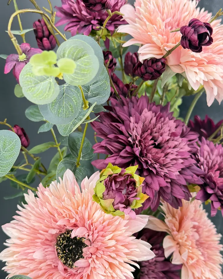 Detail van lichtroze dahlia’s, paarse bloemen en eucalyptusbladeren in boeket Lunara.