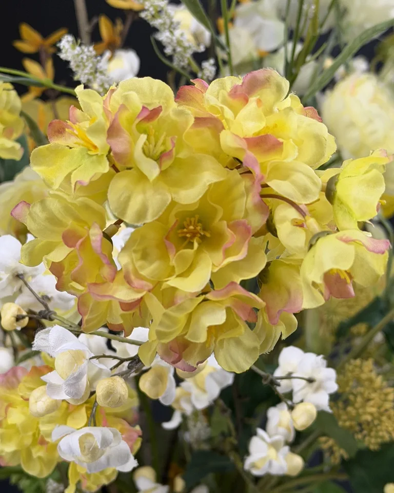 Zelora geel-wit veldboeket in groene vaas, met gele bloemen, witte bloesem en luchtige takken.