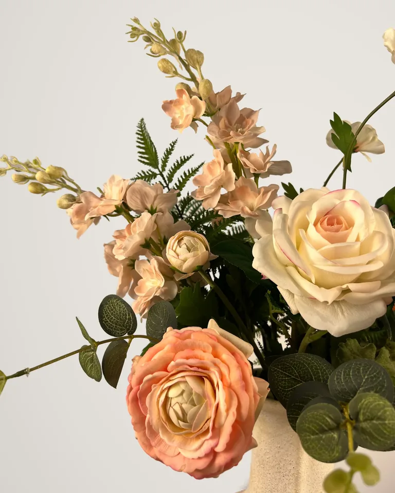 Detail van Aveline met peach ranonkels, crèmekleurige rozen en groen blad.