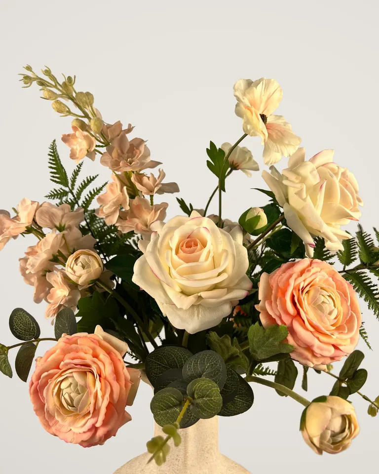 Detail van de zachte peach bloemen en groene vertakkingen in boeket Aveline.