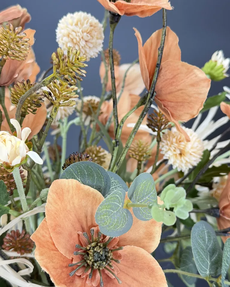 Detail van terracotta bloemen, crème pomponbloemen en eucalyptusblad in boeket Solenne.