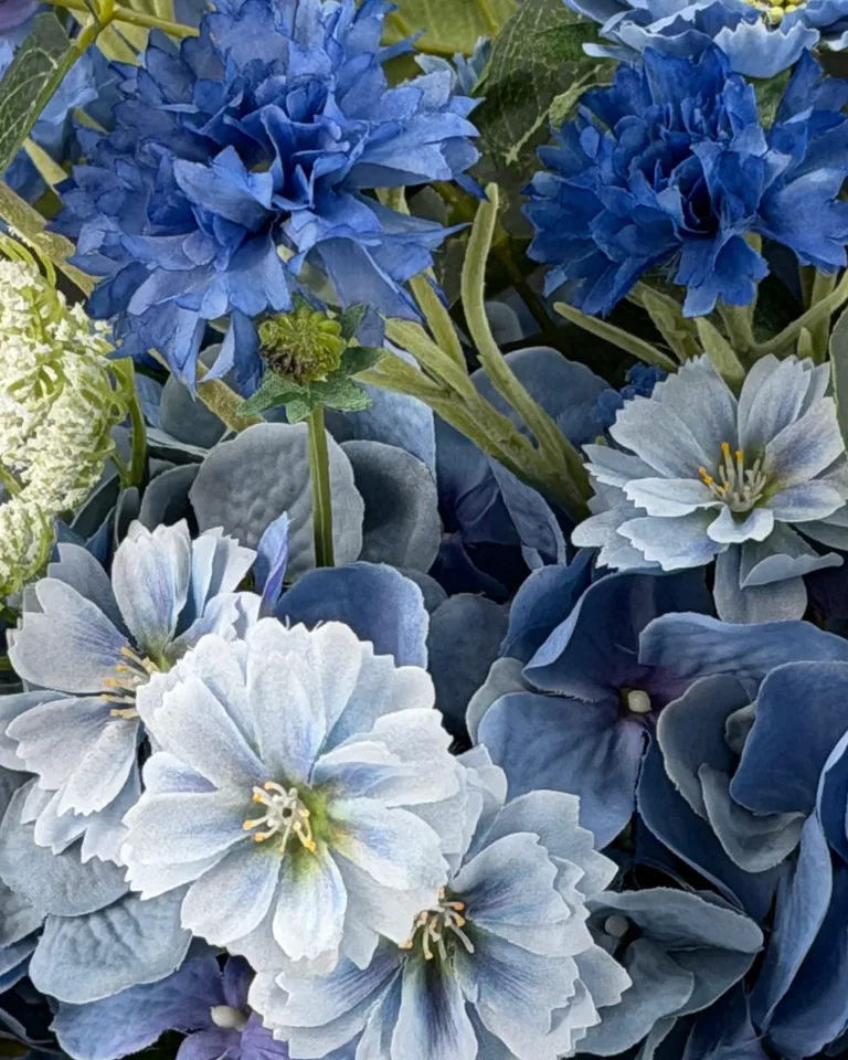 Detail van blauwe bloemen met witte bloemaccenten en groene bladeren in het blauwe boeket