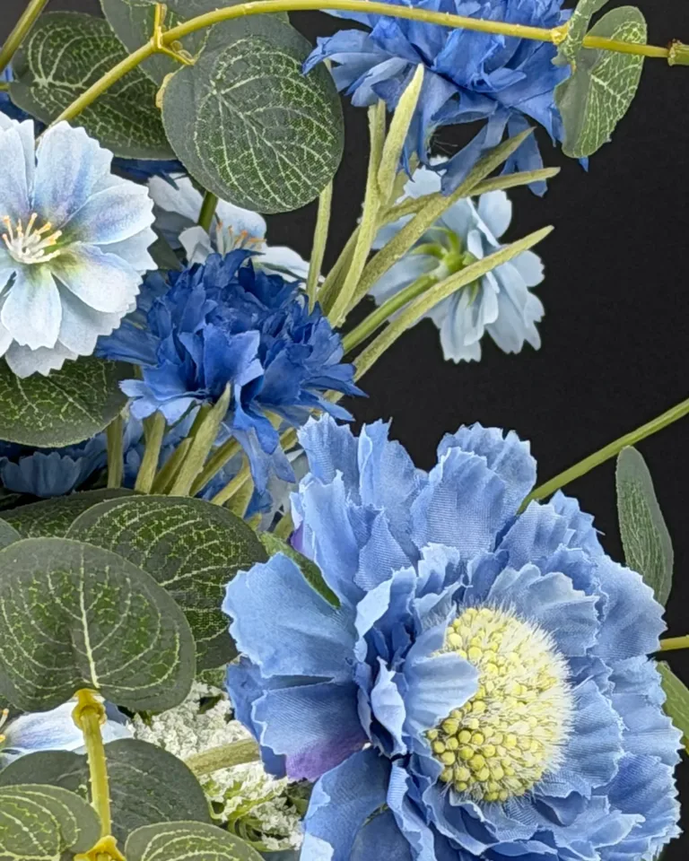 Detail van blauwe en lichtblauwe bloemen met nervenbladeren en fijne stelen in het blauwe boeket