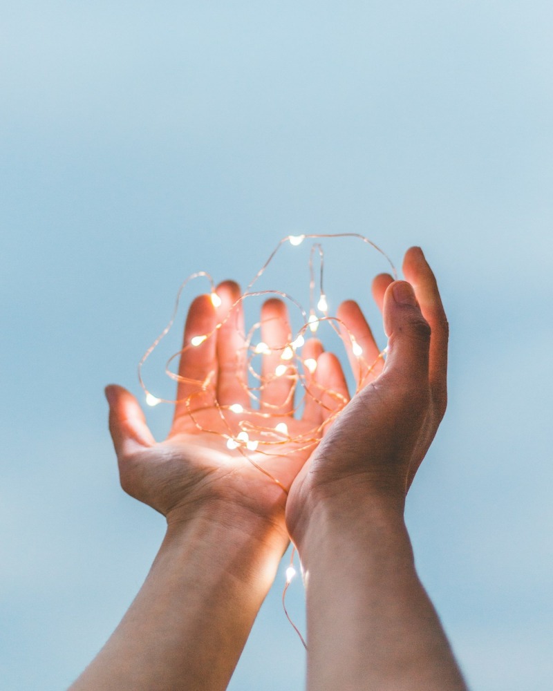 Two hands hold a ball of string with lights on it