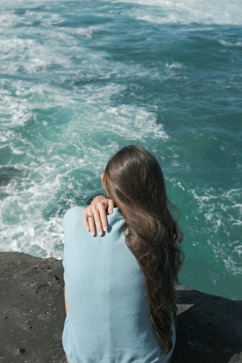 A woman sits overlooking the ocean