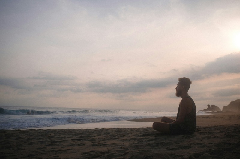 A man is sitting and meditation on the beach