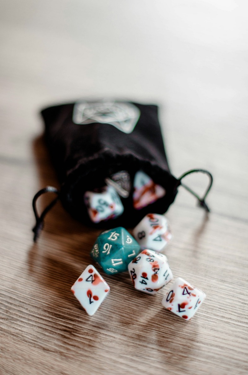 A cloth bag spilling polyhedral dice across a wooden table