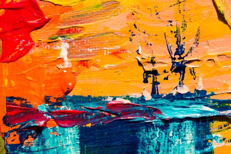 Close-up of an abstract painting with bold brushstrokes in orange, red, yellow, and teal