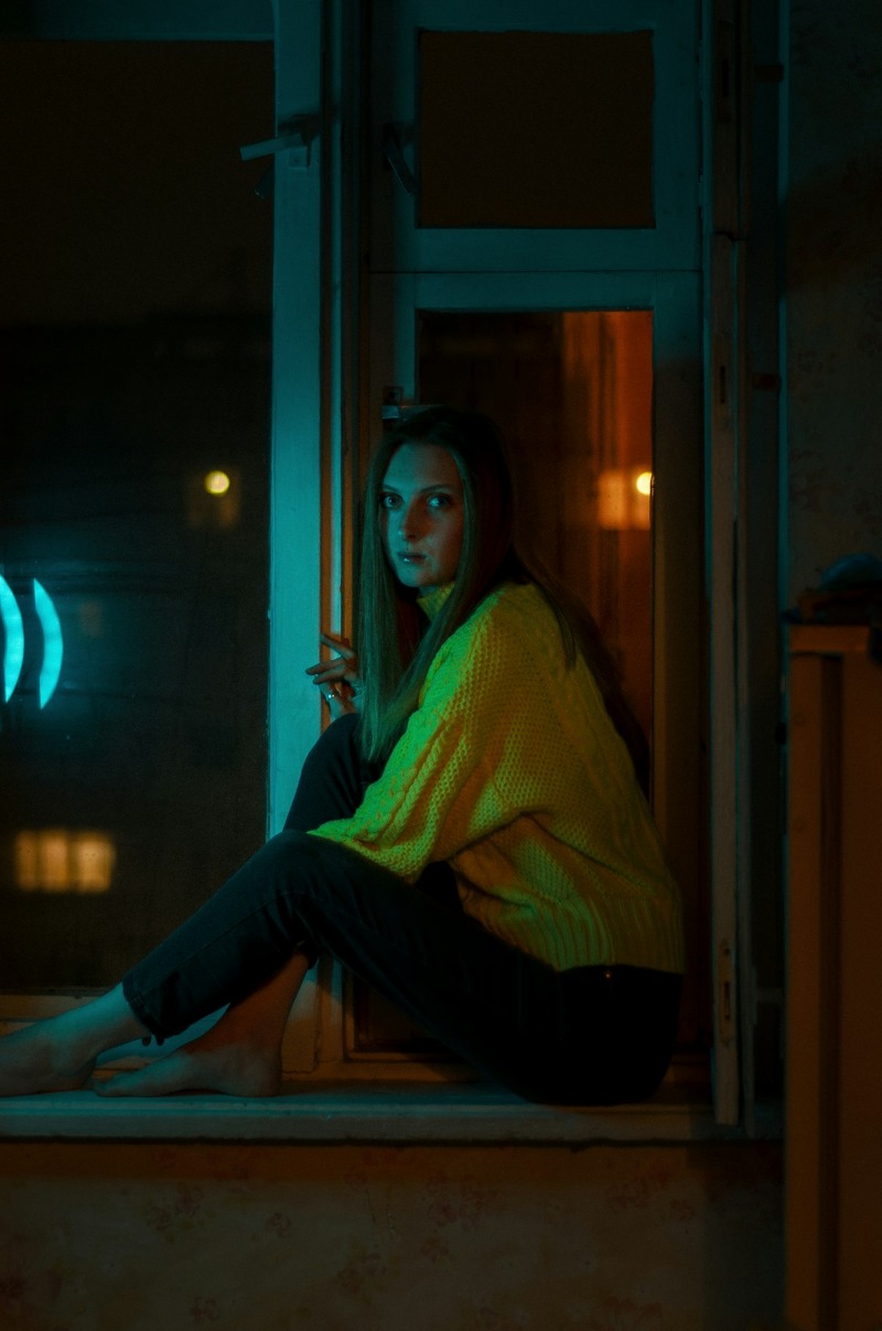 A person sitting in a doorway at night, lit by soft light
