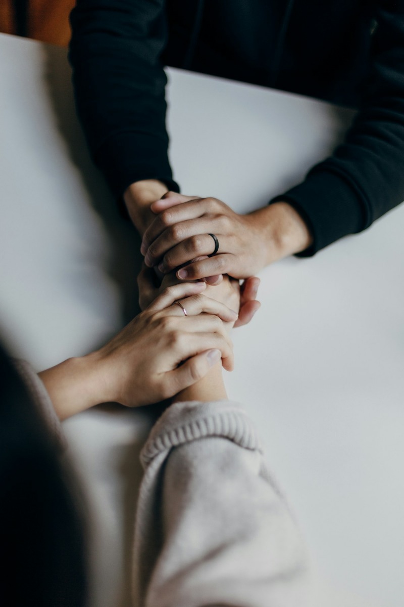Two people sitting together, one holding the other's hands