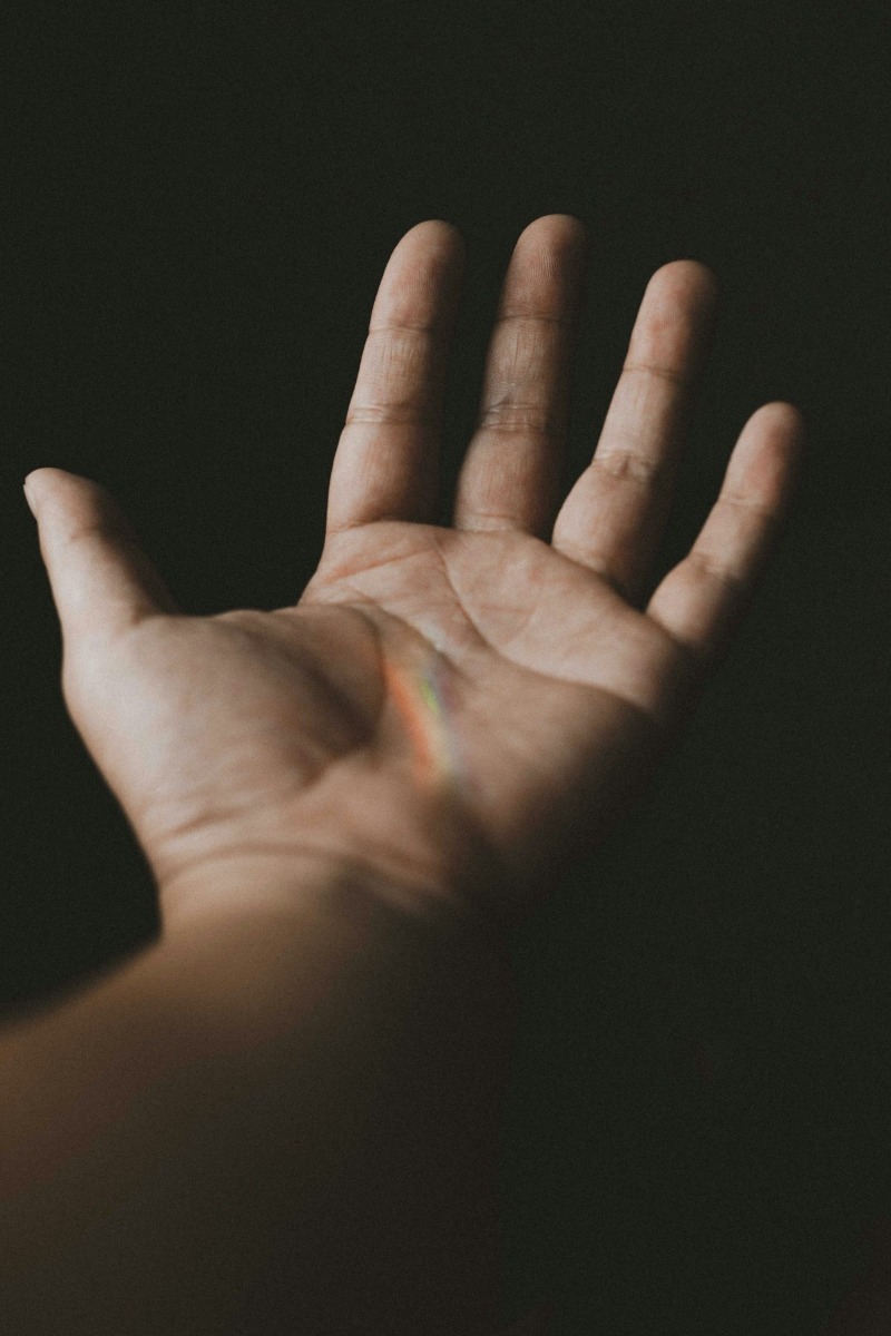 An open palm reaching out against a dark background