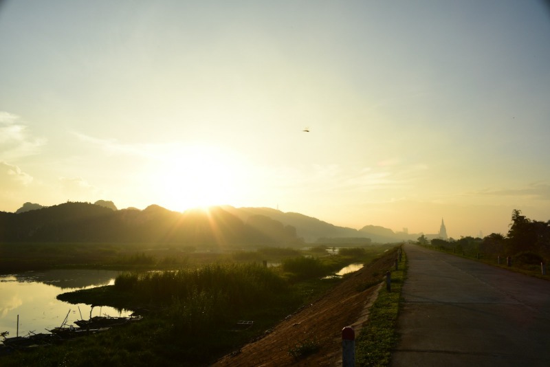 Sunrise over a valley, with a road curving into the distance