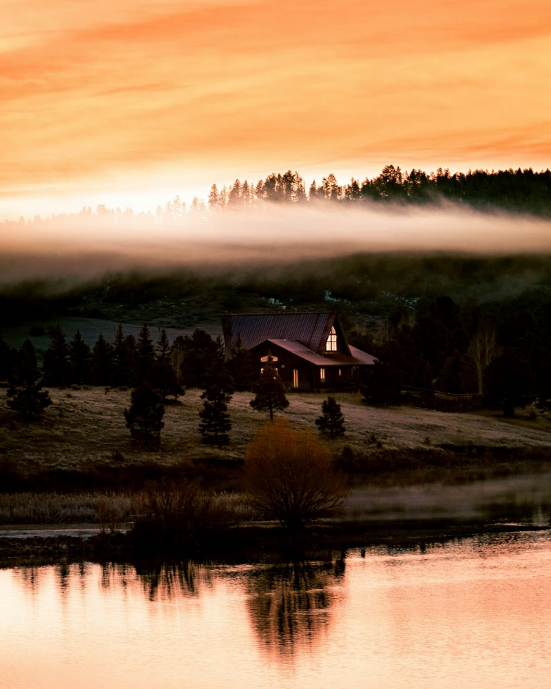 Misty sunrise over a lake with a cabin on the far shore