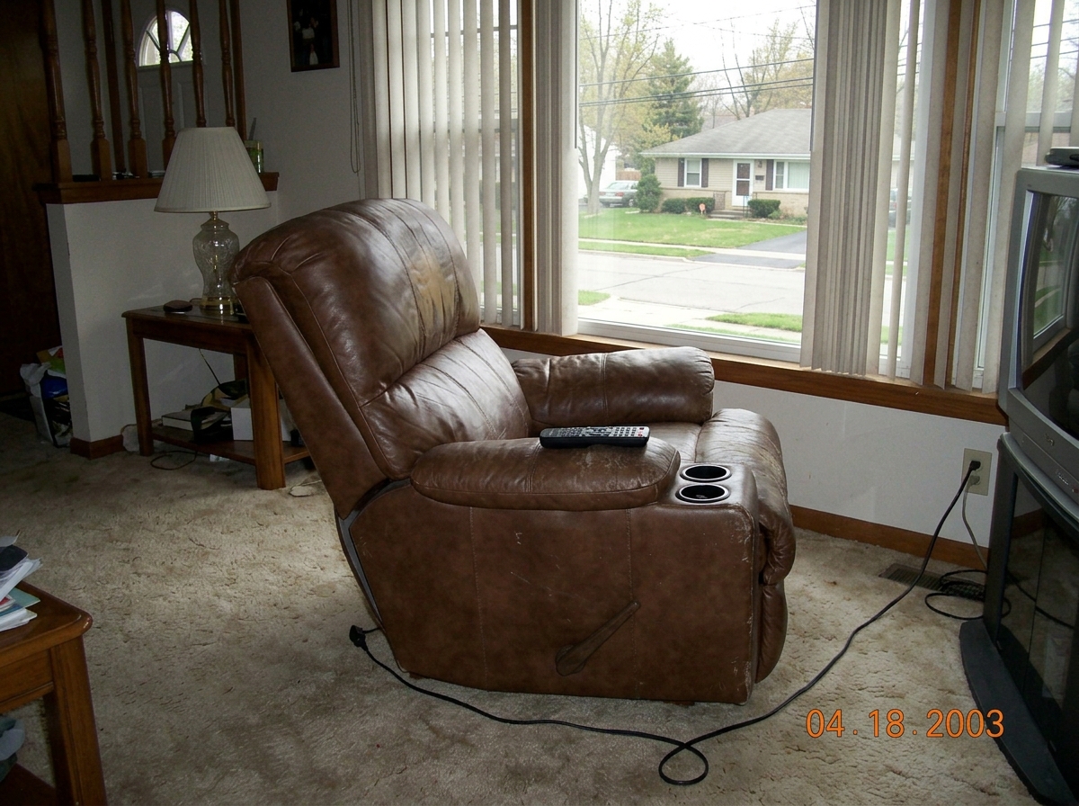 A brown leather recliner in an otherwise empty living room, seat cushion warped