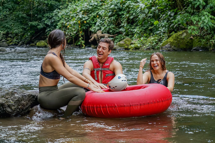 Group of friends resting by the river after tubing, enjoying the water