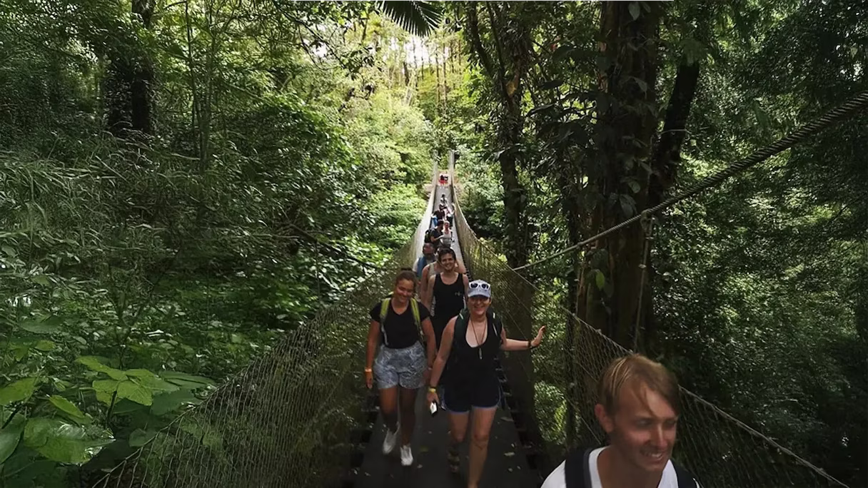 Personas pasando por puente en volcan arenal