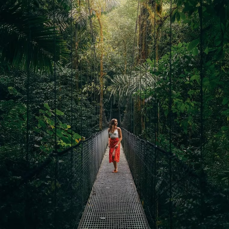 Woman in a dress smiling while enjoying nature on a hanging bridge in Mistico Arenal Hanging Bridges Park